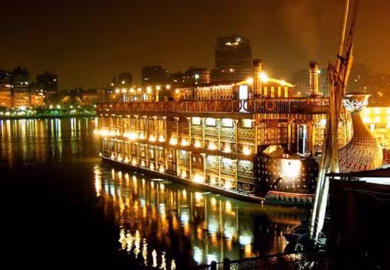 Illuminated Nile Pharaohs cruise ship at night on the River Nile in Cairo, reflecting city lights