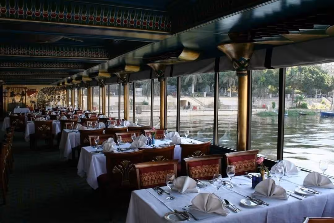 Elegant Nile cruise dining room with river views and set tables, Nile Pharaohs Cruising booking with dinner