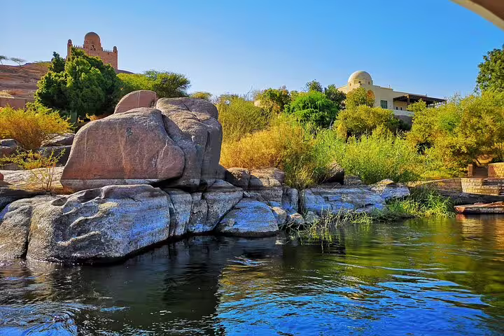 Scenic Nile River bank near Aswan with granite boulders, lush greenery, on 4 nights Luxor Nile cruise tour