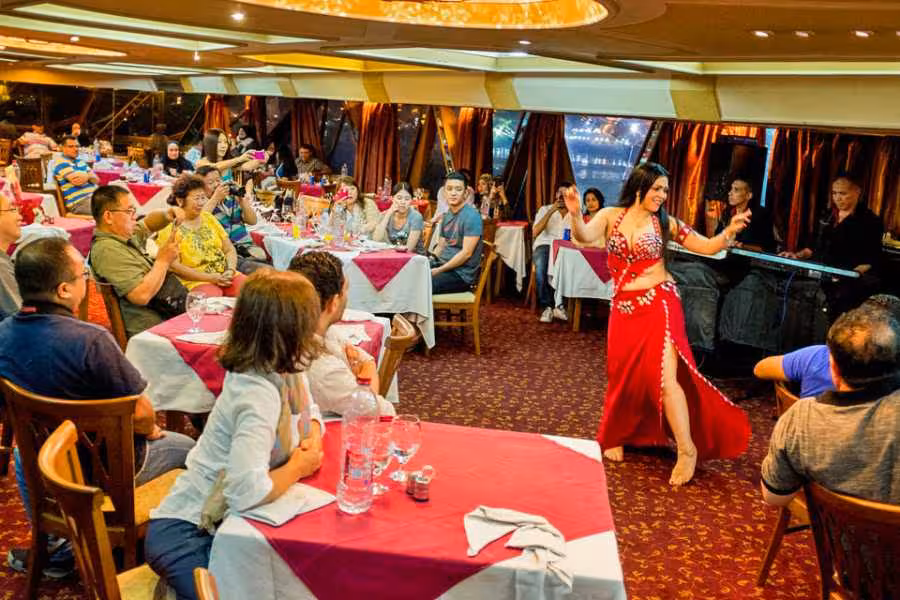 Belly dancer performs on Nile River night dinner cruise in Cairo with buffet tables and live music onboard