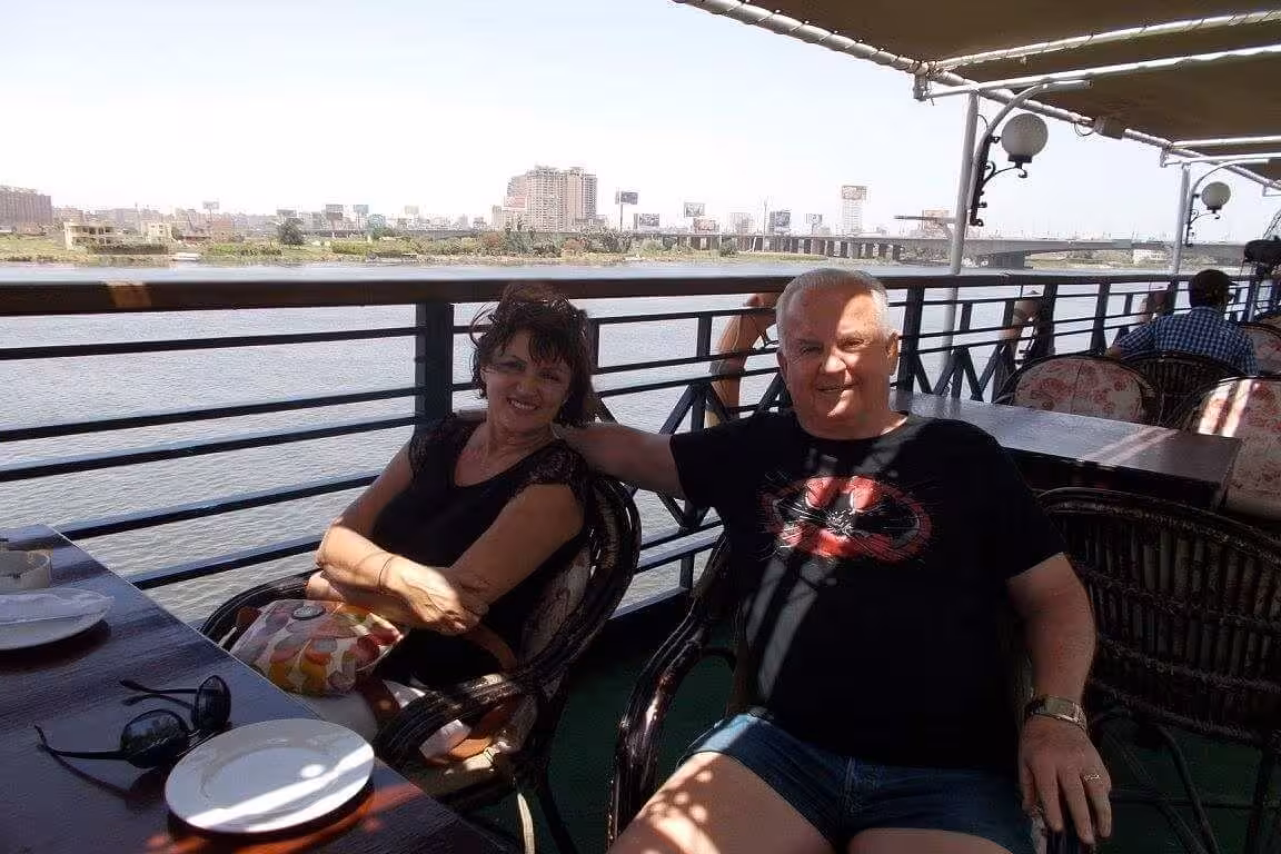 Couple relaxing on open-air deck during Nile River dinner cruise in Cairo, with river views and skyline