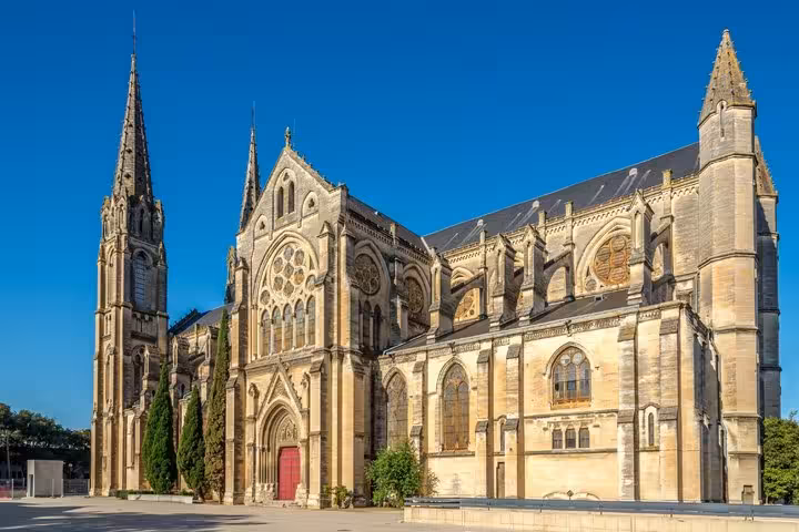 Gothic cathedral with tall spire and ornate facade in Nimes, France under clear blue sky