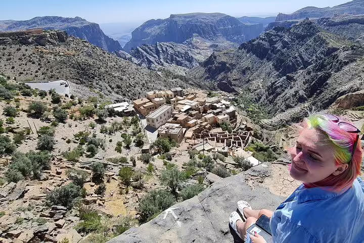 Traveler enjoys panoramic view of ancient village nestled in the rugged mountains of Jebel Akhdar, Oman.