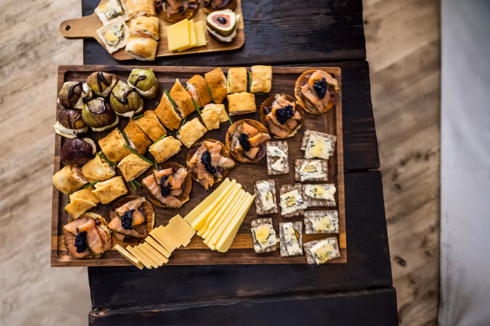 Elegant Nordic appetizer board with smoked salmon blinis, blue cheese crackers, figs, and sliced cheese for a northern lights dinner experience