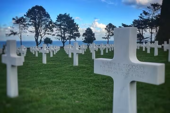Rows of white crosses at Normandy American Cemetery overlooking the D-Day beaches on a sunny day