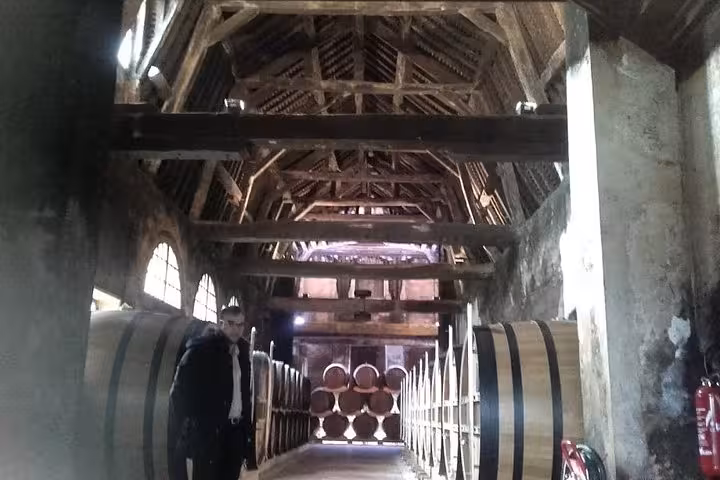 Traditional Normandy cider cellar with oak barrels, visited on a private Bayeux food tour featuring local tastings