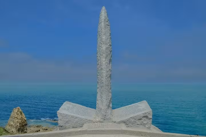Granite obelisk memorial monument overlooking the Normandy coastline on a clear blue day
