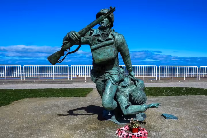 Bronze WWII soldier statue at Normandy D-Day beaches memorial with floral wreath tribute