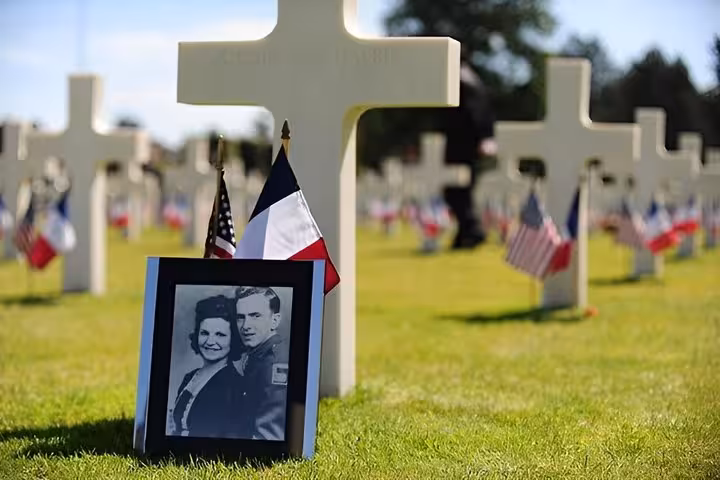 White crosses and French and American flags at Normandy American Cemetery with a WWII soldier portrait