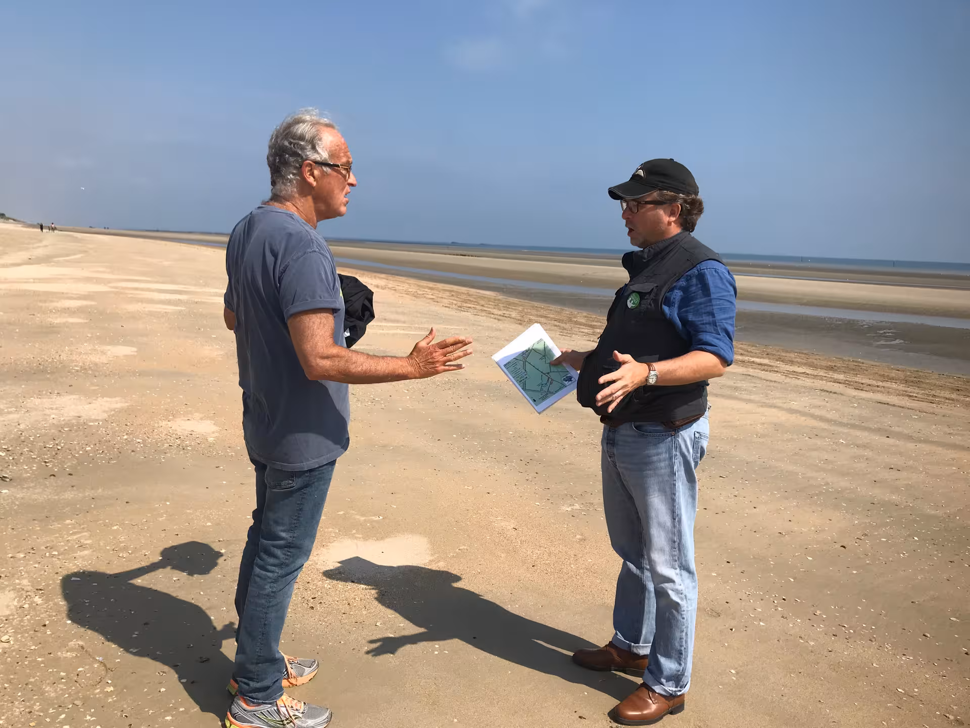 Two men discussing a map on a Normandy D-Day beach near Le Havre on a clear day