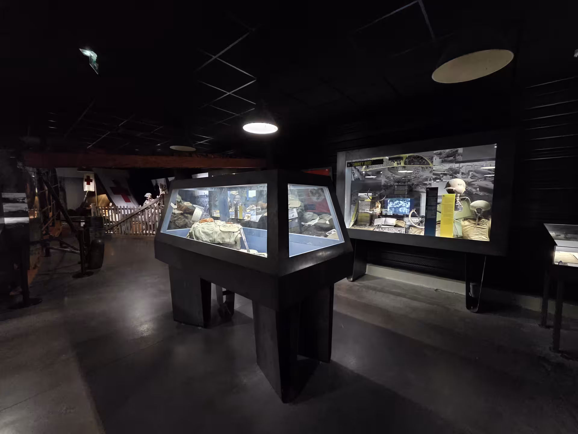 Dimly lit WWII museum display cases featuring D-Day artifacts on a private guided Normandy tour