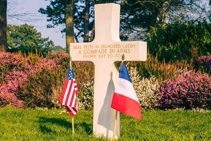 Unknown soldier grave cross with US and French flags at Normandy American Cemetery, D-Day beaches