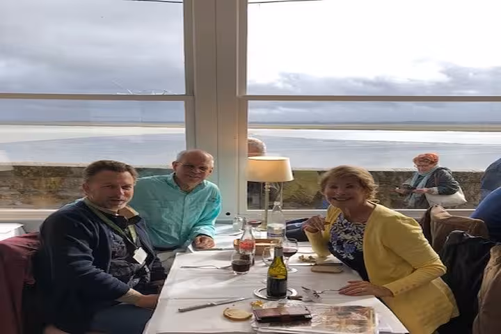 Tourists dining at seaside restaurant in Normandy with wine and local food during private food tour
