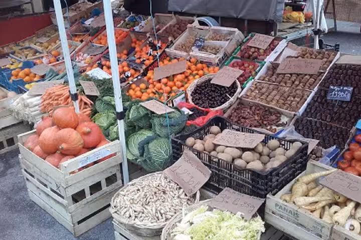 Colorful outdoor market stall with fresh vegetables, fruits, mushrooms, and root vegetables in crates and baskets
