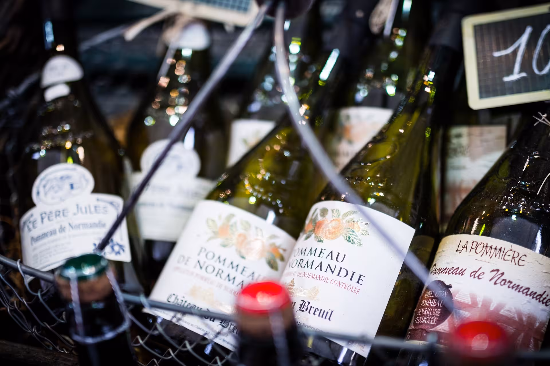 Bottles of Normandy pommeau and cider in a market stall, featured drink tasting on the Gourmet Market Tour