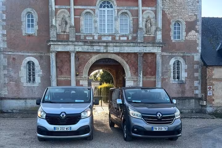 Two Renault Trafic vans parked in front of a historic French château gateway in Normandy