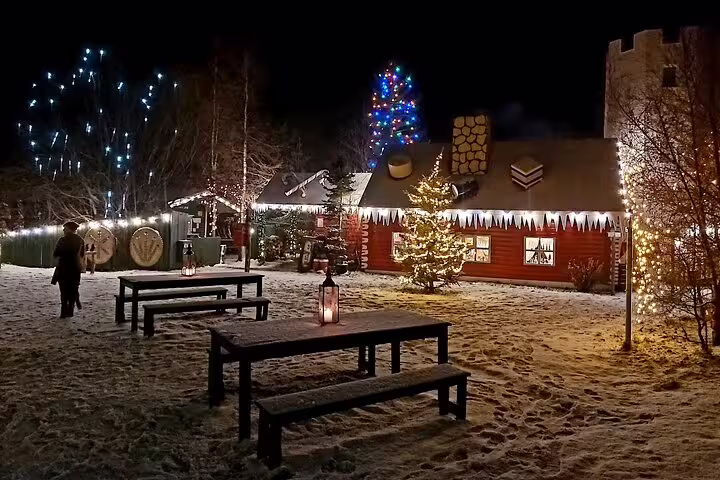 Christmas House in North Iceland at night with snow, festive lights, decorated trees, and outdoor picnic benches