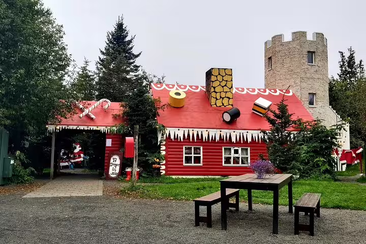 Red Christmas-themed house with candy cane decorations and stone tower in North Iceland