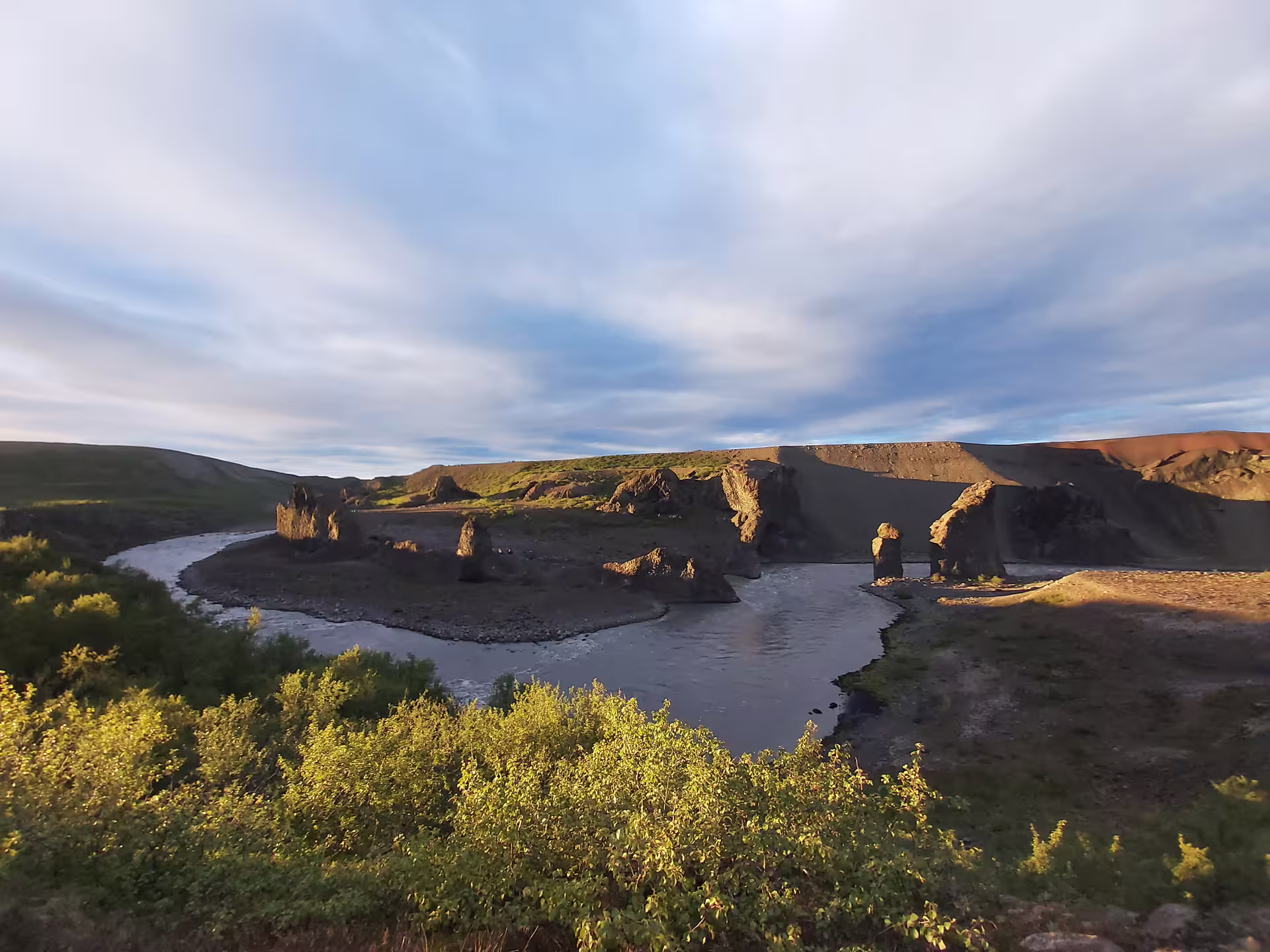 Rocky basalt columns along a winding glacial river in a volcanic canyon in North Iceland