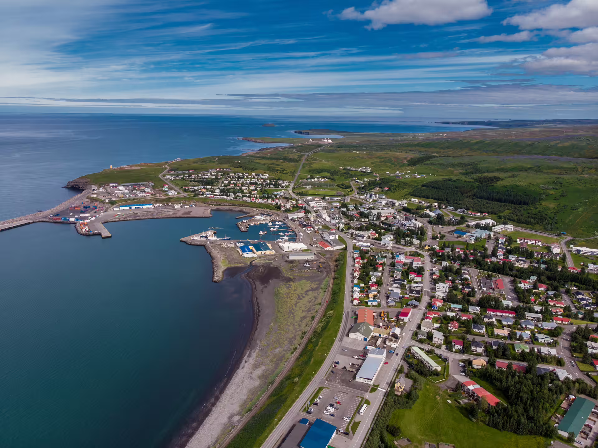 Aerial view of a coastal town in North Iceland with harbor, colorful rooftops, and blue ocean waters