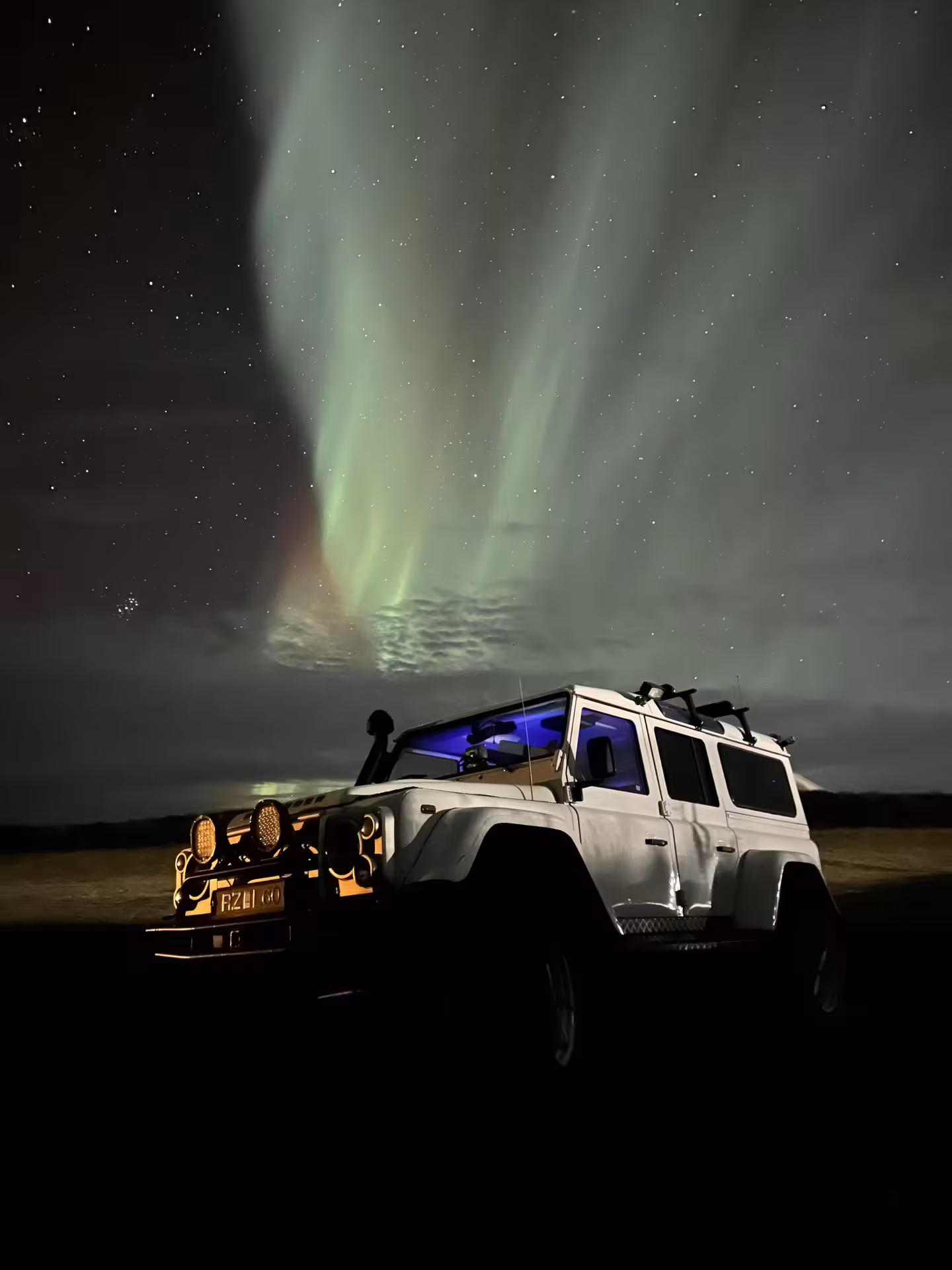 4x4 vehicle under Northern Lights on Akureyri tour, highlighting Iceland's mesmerizing aurora borealis experience.