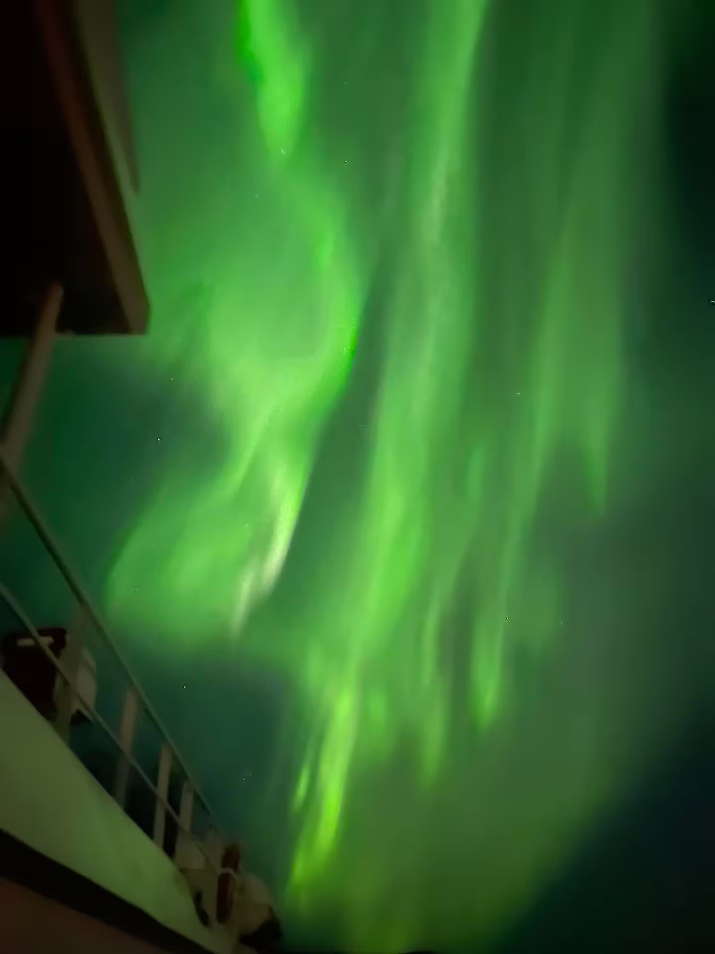 Vivid green northern lights aurora borealis filling night sky viewed from boat deck in Reykjavik