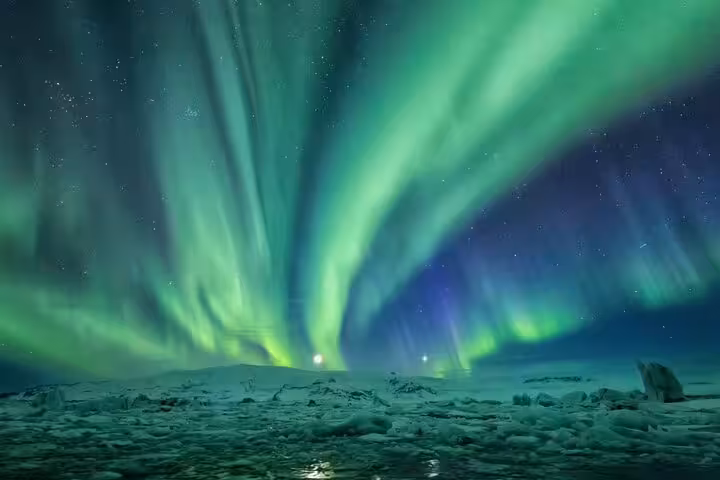 Vivid green and purple aurora borealis swirling over a frozen Arctic landscape at night