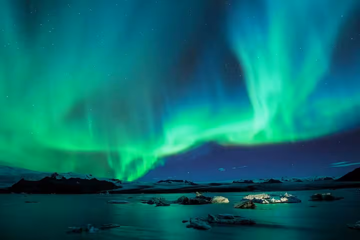 Vibrant green aurora borealis dancing over icy glacial lagoon in Iceland at night