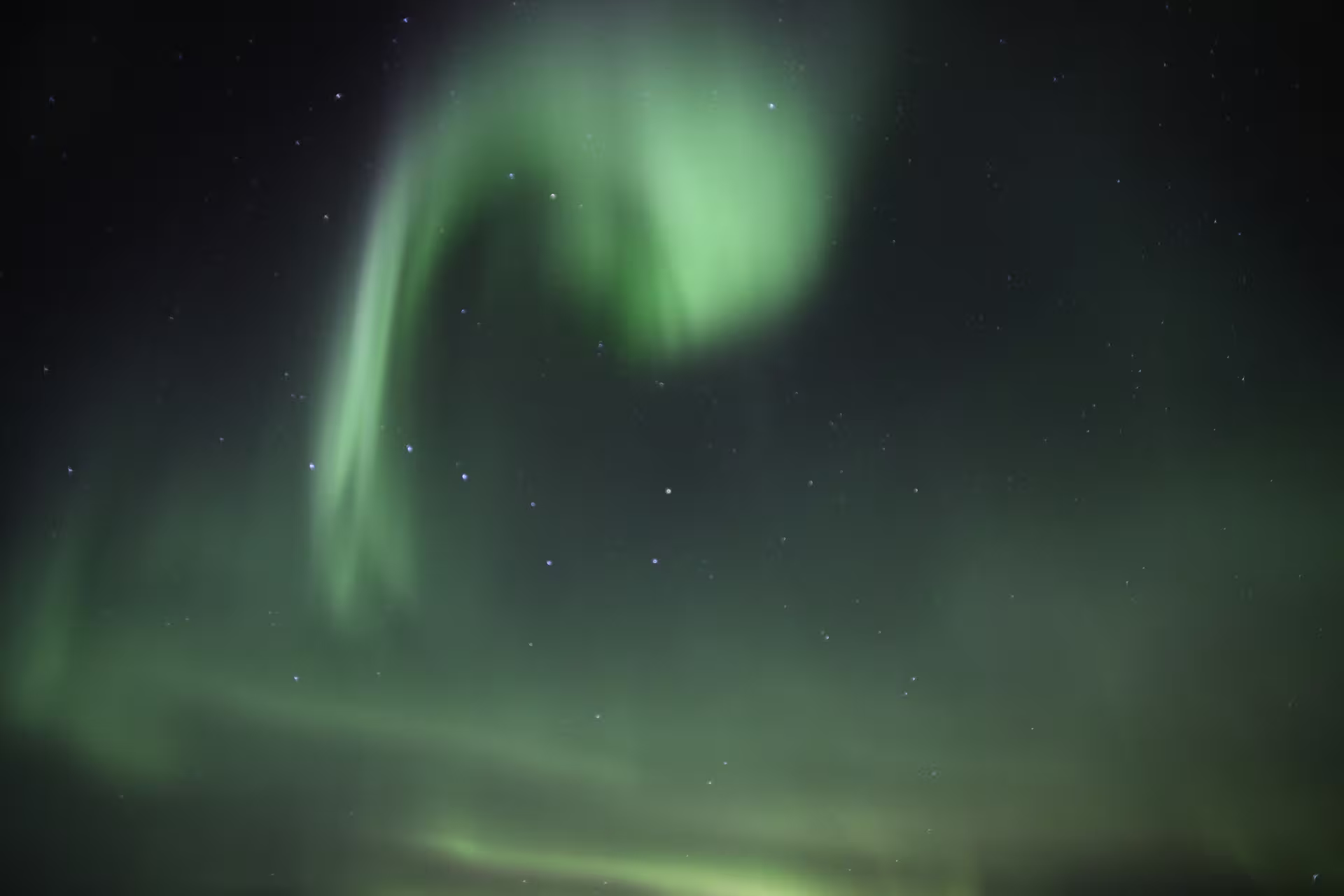 Vivid green aurora borealis swirling in a starry night sky over Iceland
