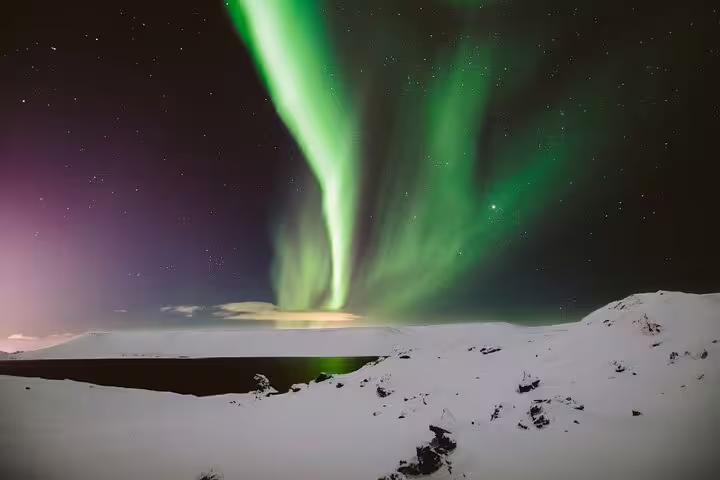 Vivid green and purple aurora borealis swirling over snow-covered Arctic landscape at night