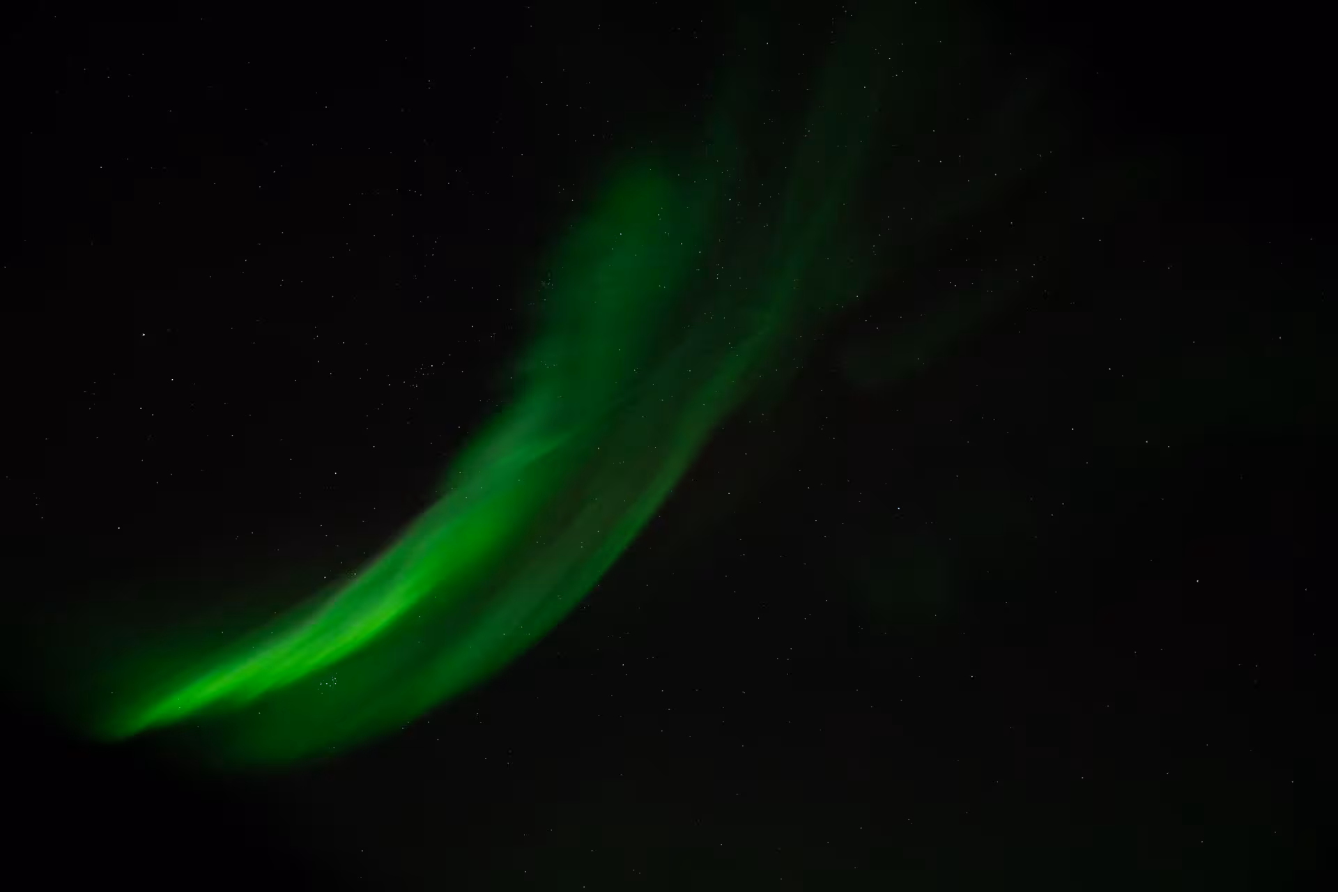 Vivid green northern lights aurora borealis sweeping across the dark night sky in Iceland