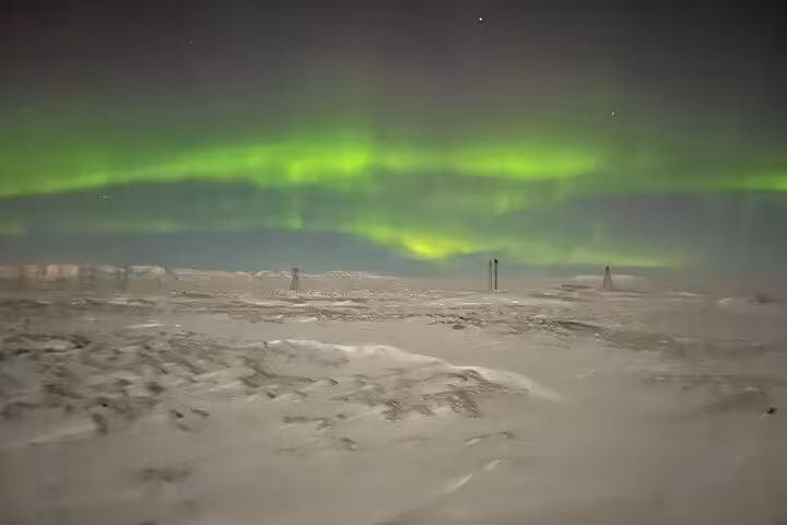 Vibrant green aurora borealis dancing over a snowy arctic landscape at night