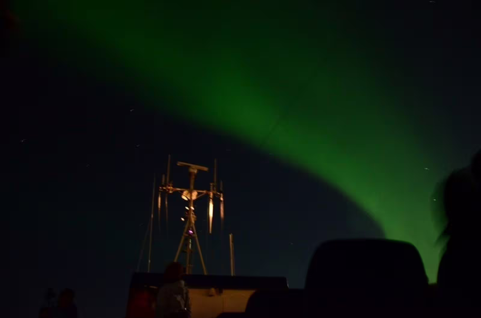Aurora borealis green northern lights over a boat mast on a night cruise in Reykjavik Iceland