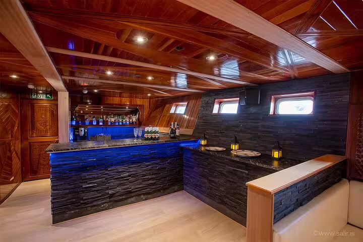 Luxury bar lounge with blue LED lighting and dark stone walls inside a Northern Lights boat in Reykjavik