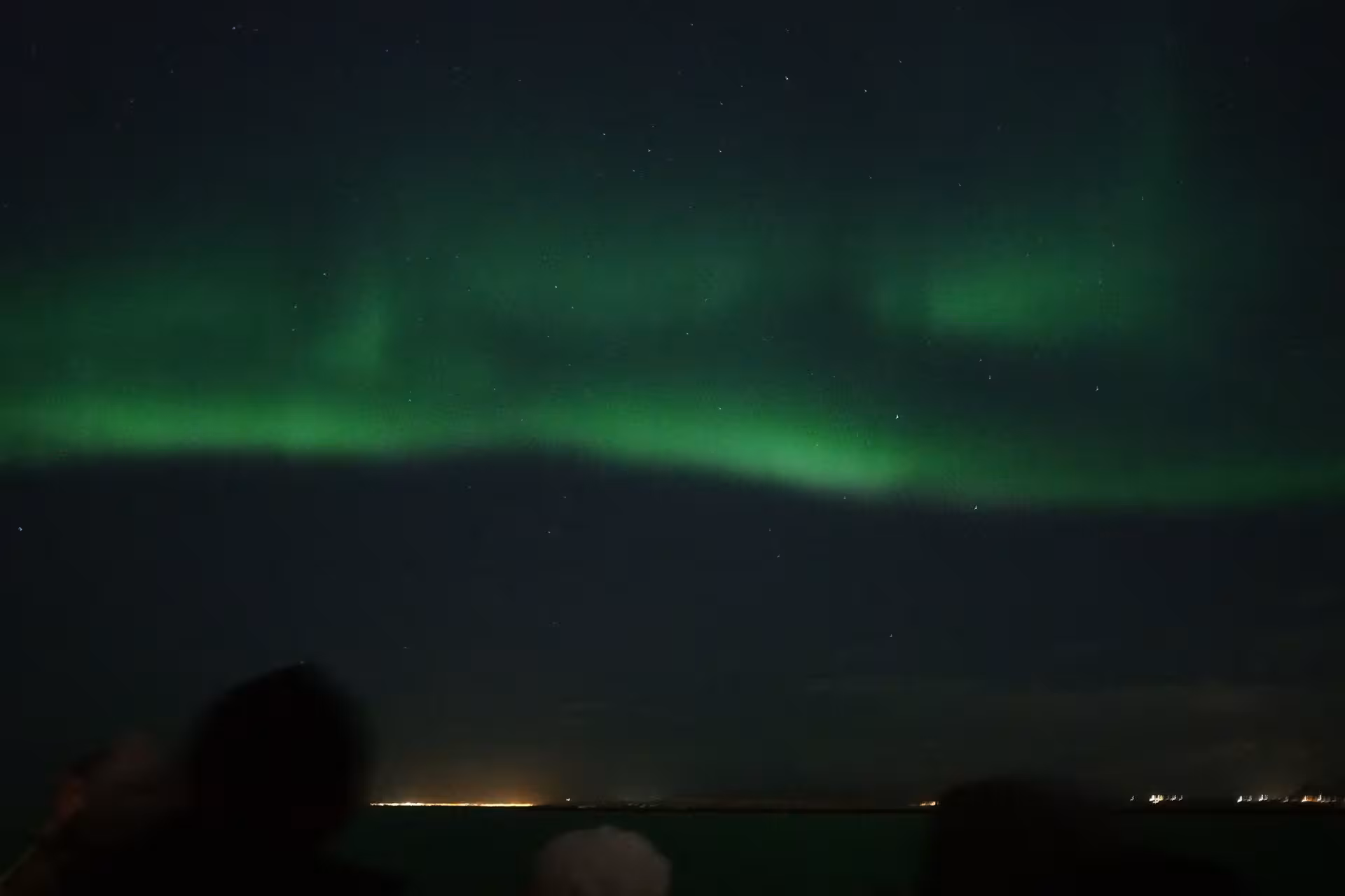 Travelers watching the Northern Lights from a boat near Reykjavík