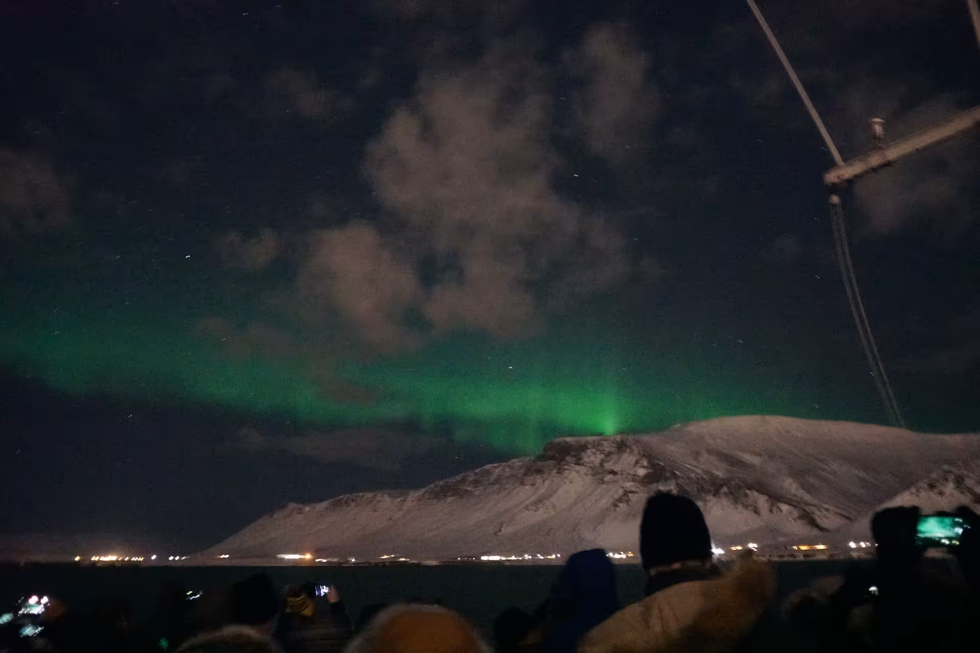 Colorful Northern Lights arching above a boat in Reykjavík