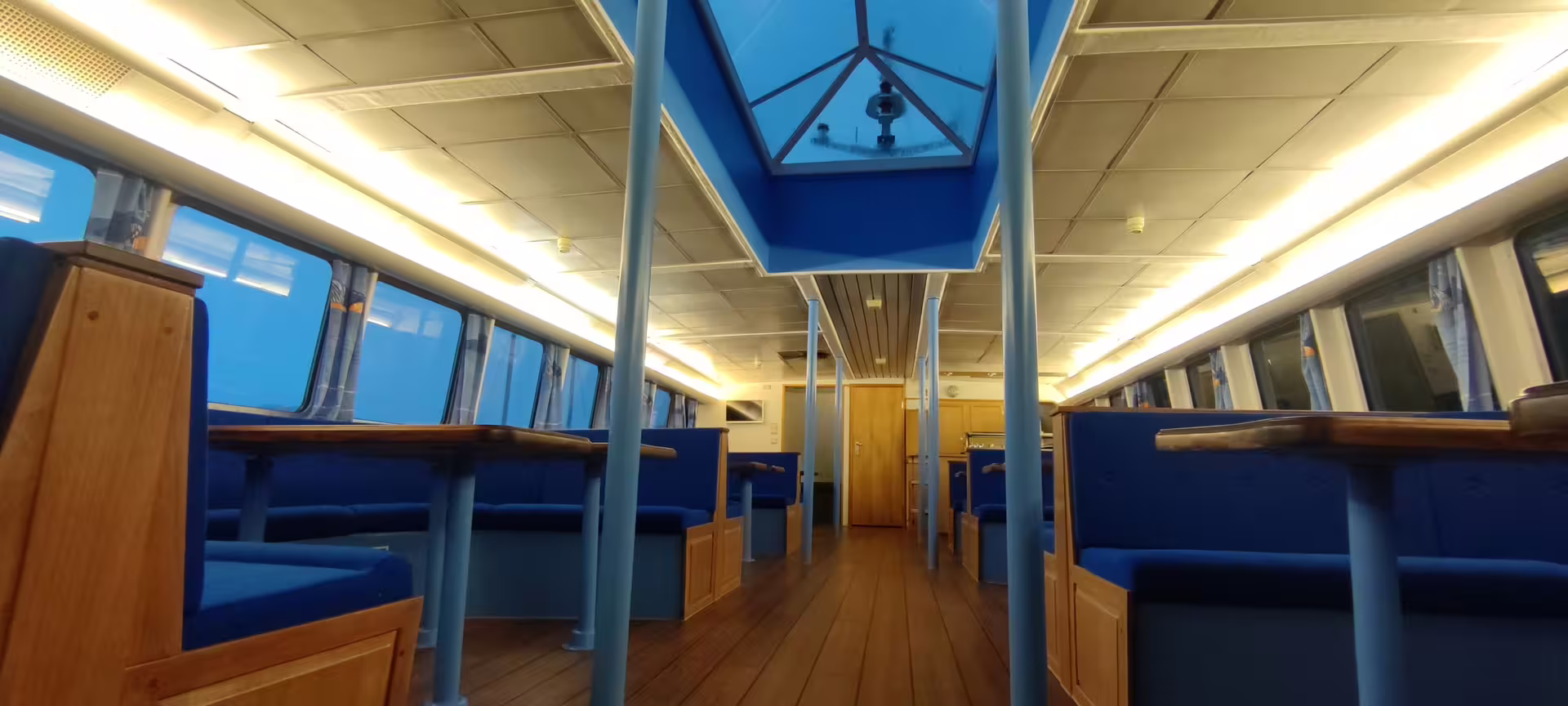 Empty blue upholstered seating cabin interior of a Northern Lights night cruise boat in Reykjavik