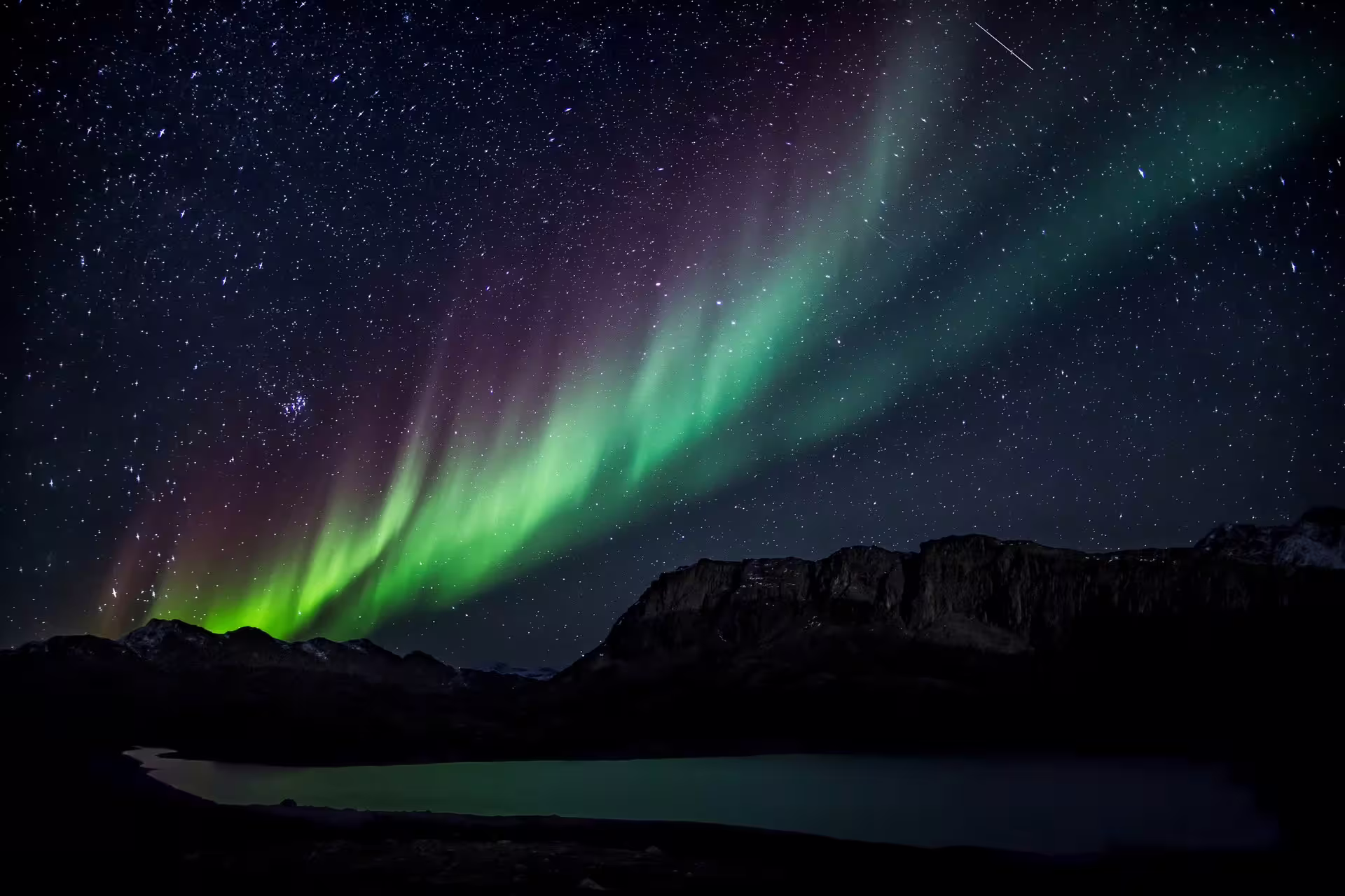 Aurora borealis with green and purple lights over mountain lake in Reykjavik Iceland night sky