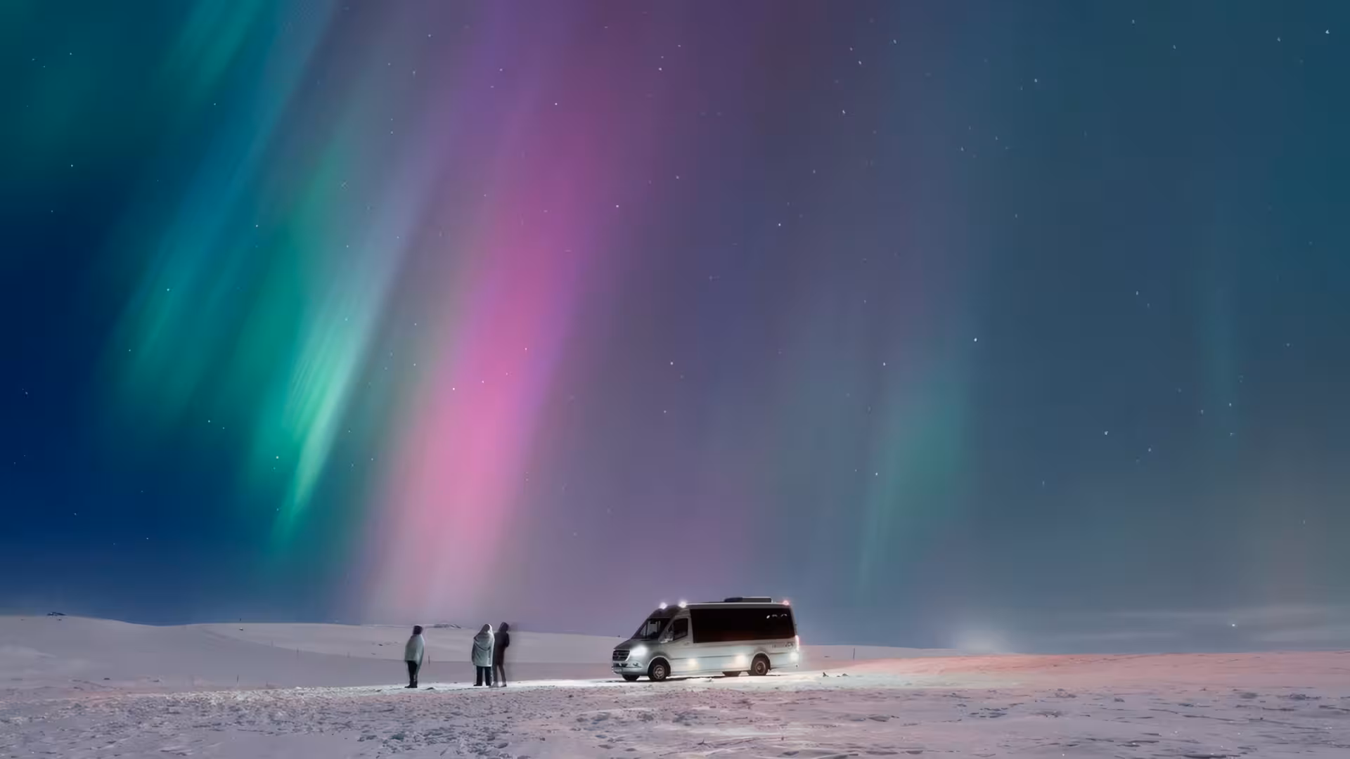 Small group watching vibrant green and purple northern lights over snowy Iceland landscape with tour van