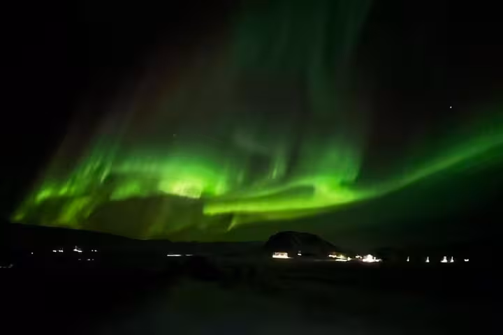 Vivid green northern lights dancing across the night sky over Reykjavik Iceland