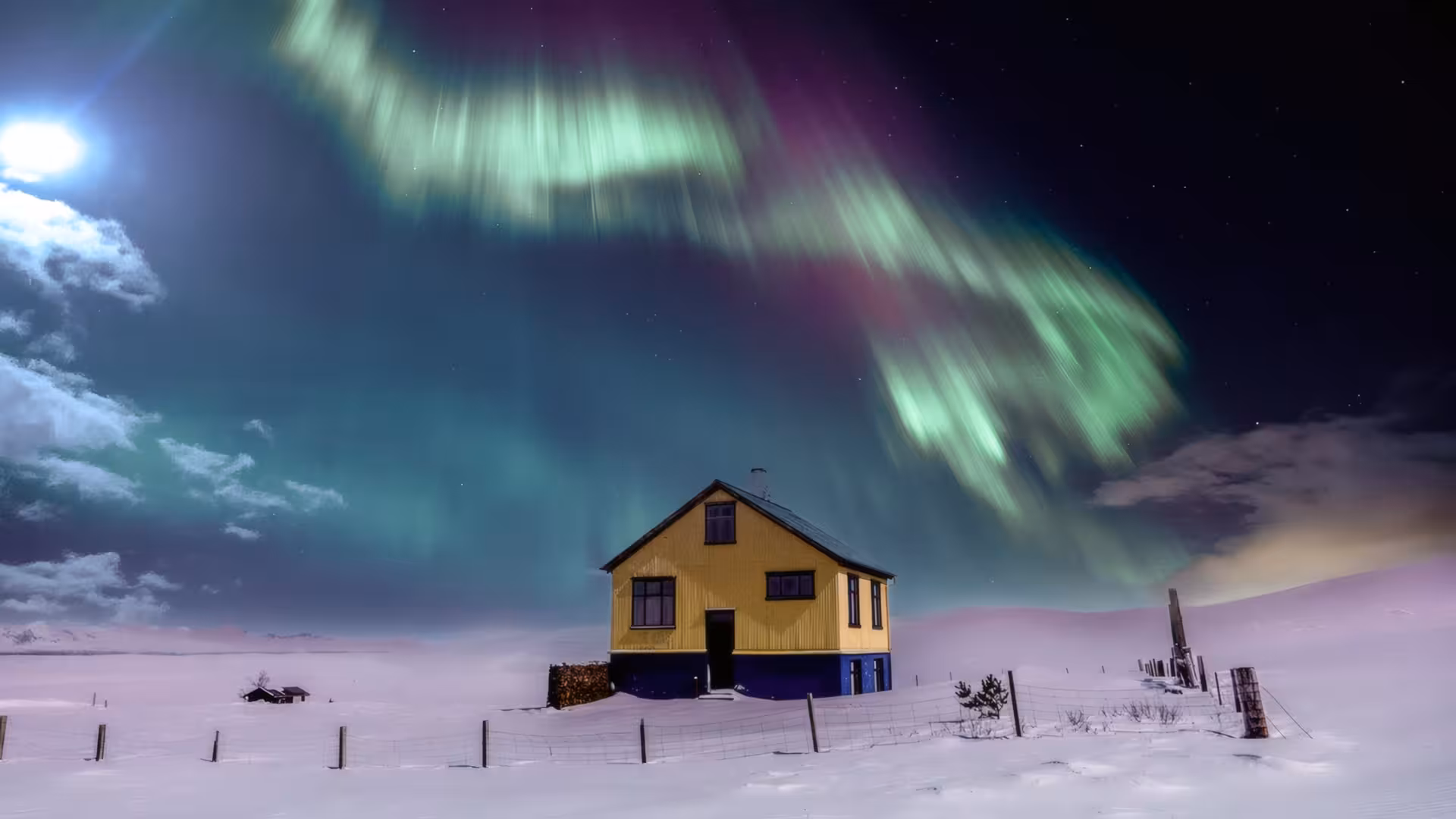 Yellow house under vibrant green aurora borealis northern lights in snowy Iceland winter night