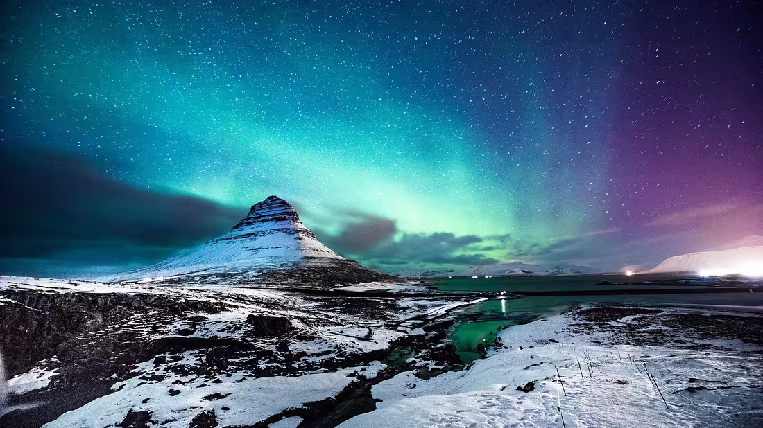 Northern Lights in the sky at night, above a uniquely shaped mountain