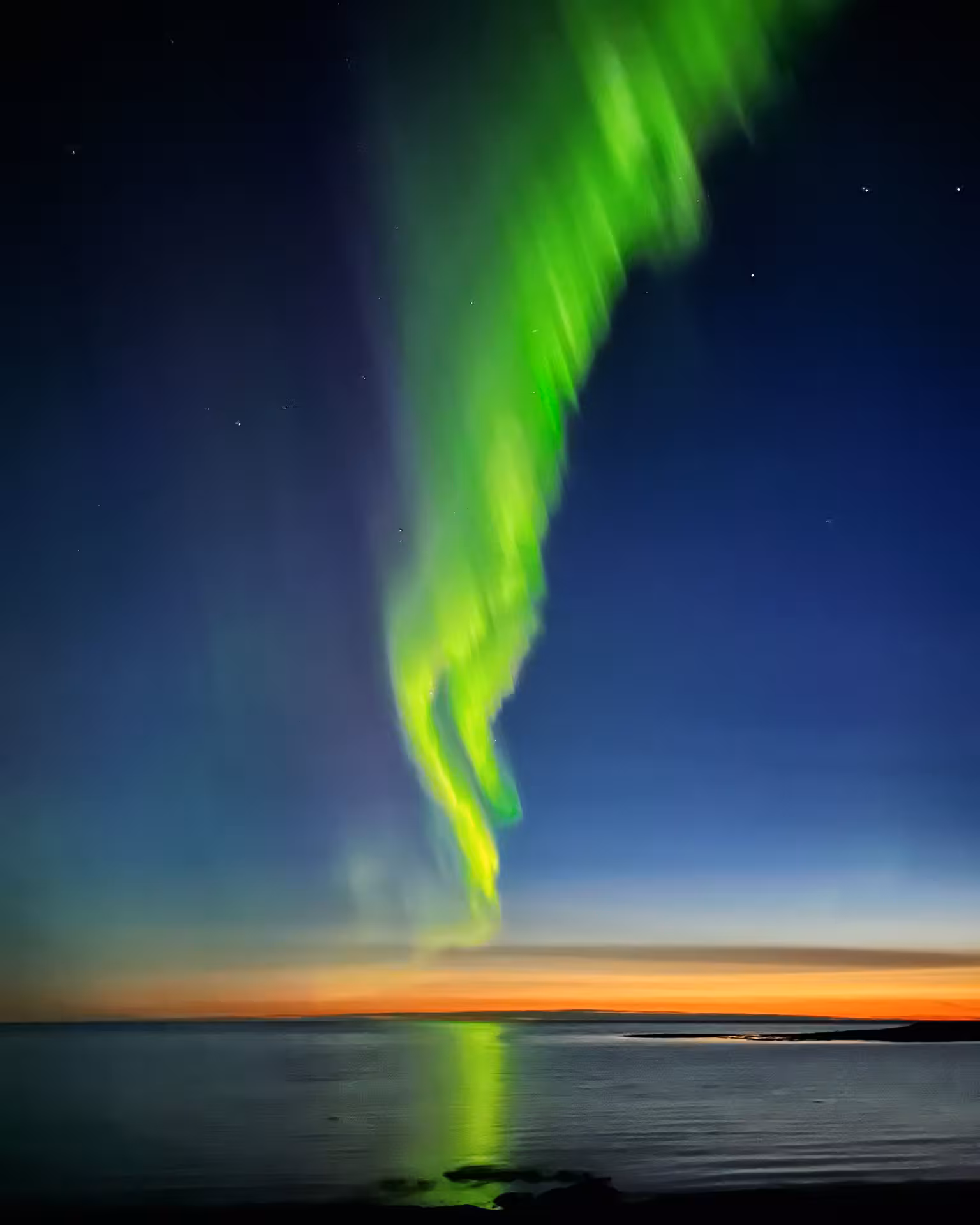 Witness the breathtaking Northern Lights over Iceland's serene coastline on the women-only winter tour.