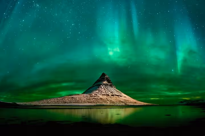 Aurora borealis northern lights illuminating green sky over Kirkjufell mountain Iceland at night