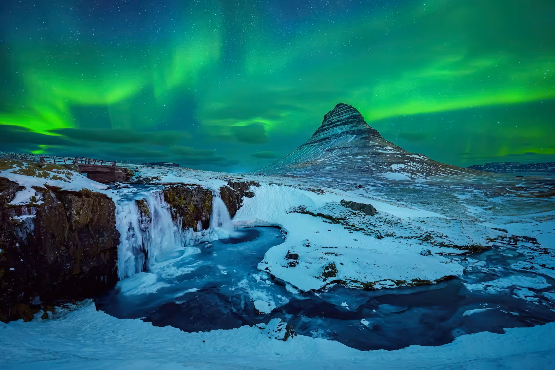 Northern lights aurora borealis over Kirkjufell mountain and frozen waterfall in Iceland at night