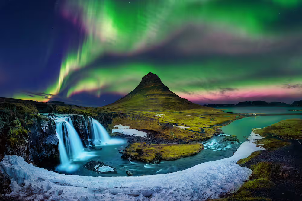 Aurora borealis over Kirkjufell mountain with waterfall and snow in Iceland at night