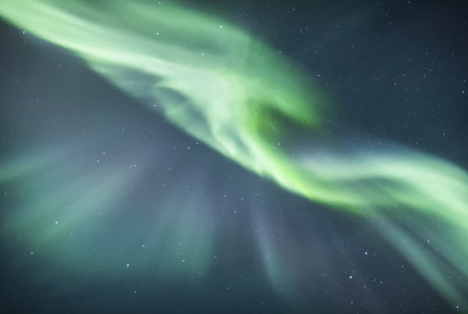 Vivid green northern lights swirling across a starry night sky in Iceland