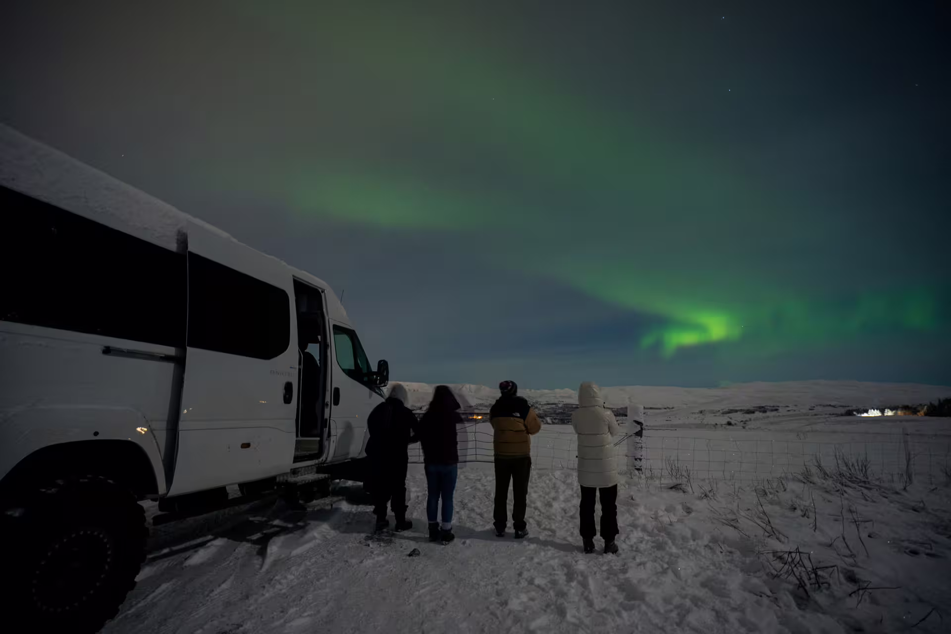 People standing beside of a Super Jeep watching the Aurora.