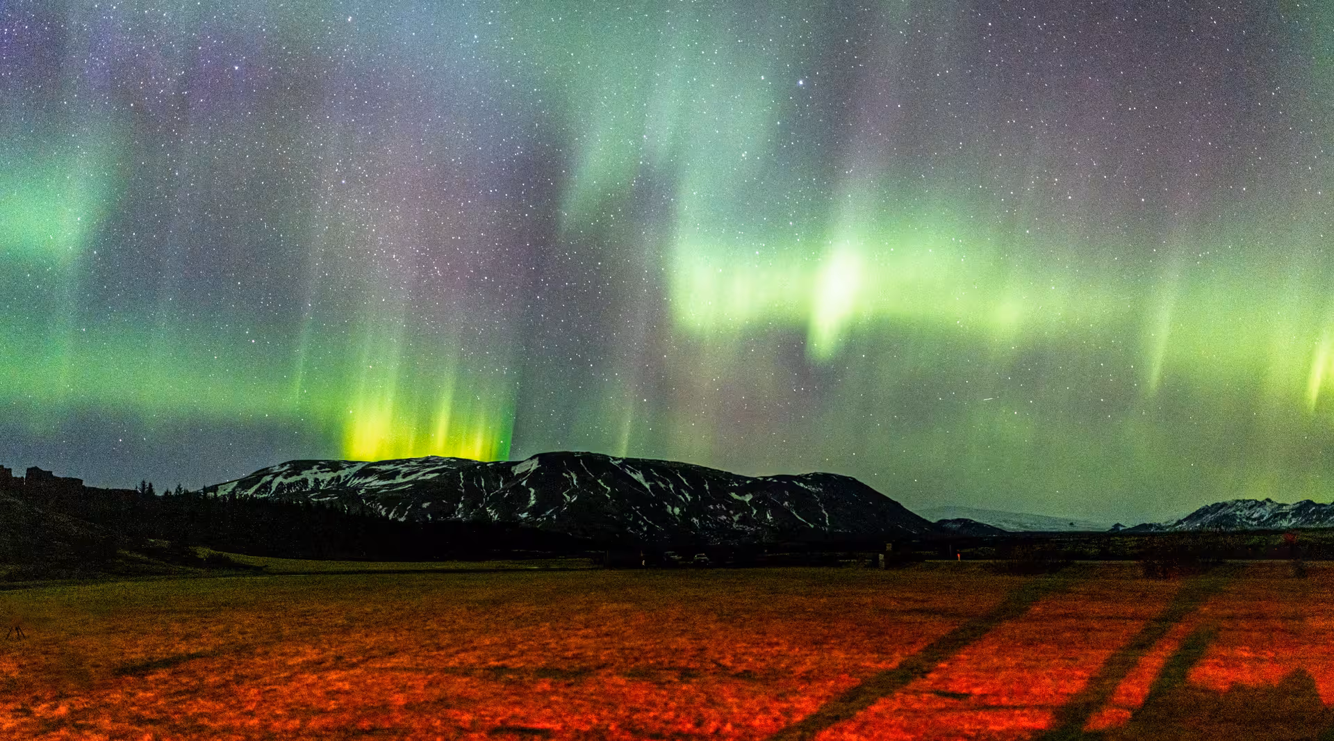 Vibrant green northern lights aurora borealis over snow-capped mountains near Reykjavik, Iceland at night