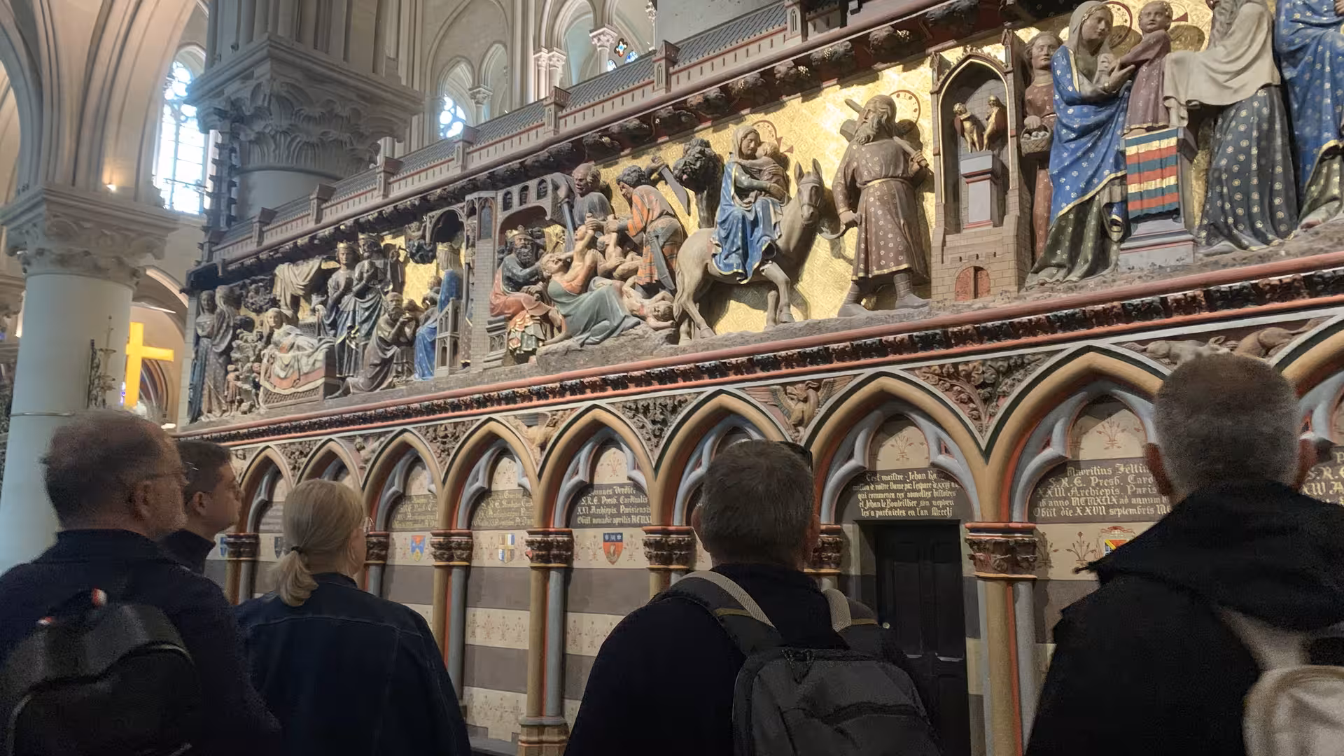 Tourists admiring ornate polychrome sculptural reliefs on Notre-Dame Cathedral choir screen, Paris
